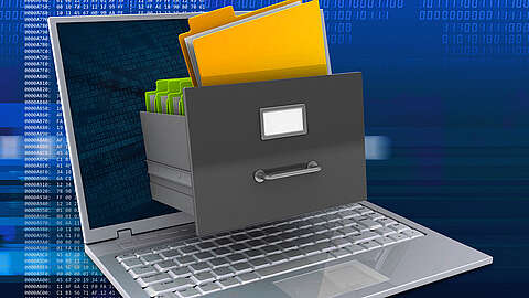 Ein Laptop mit einer aus dem Bildschirm herausfahrenden Aktenschrankschublade, die gelbe und grüne Ordner enthält, symbolisiert die digitale Dateispeicherung oder Datenorganisation. Der blaue digitale Code-Hintergrund unterstreicht das Tech-Thema.