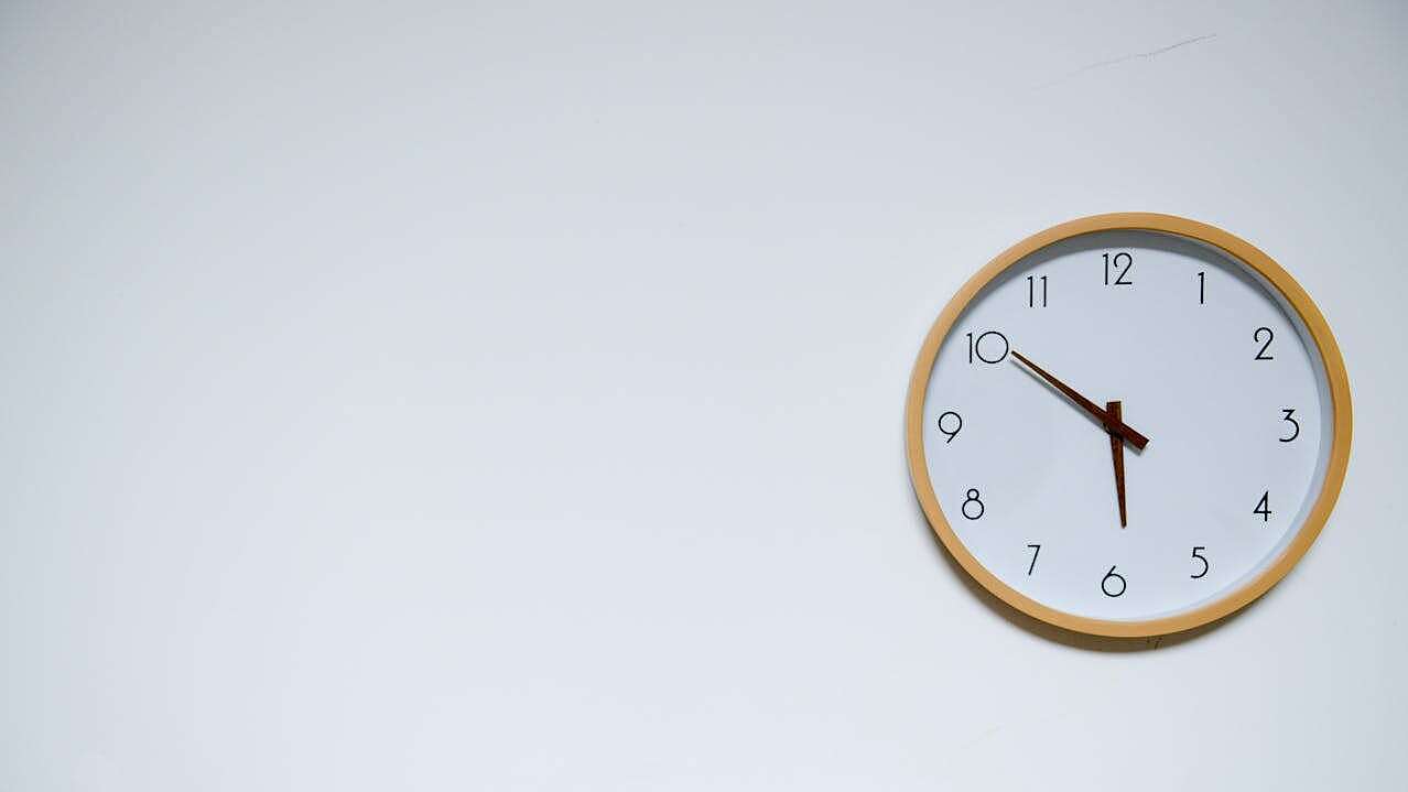 Ersparnis von Zeit und Ressourcen Eine Uhr hängt an einer weißen Wand